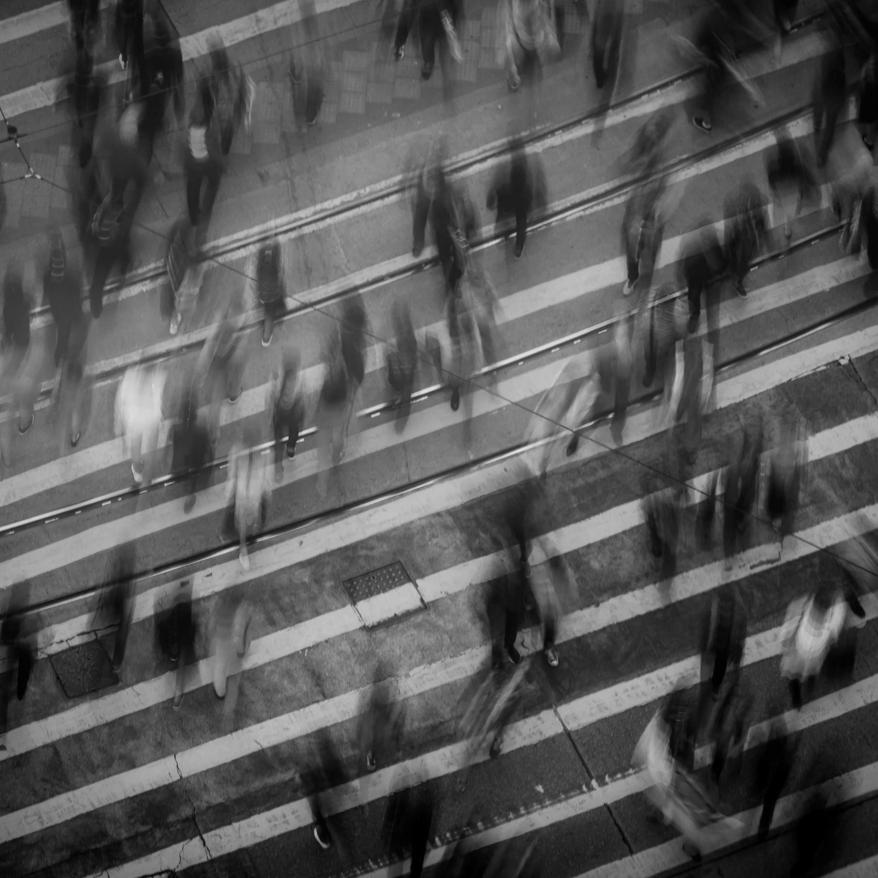 Picture of pedestrian crossing with people walking over it in gray and a bit blured.